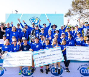 Challenged Athletes Foundation supporters holding oversized cheques at a fundraising event, with the CAF logo on the backdrop behind them