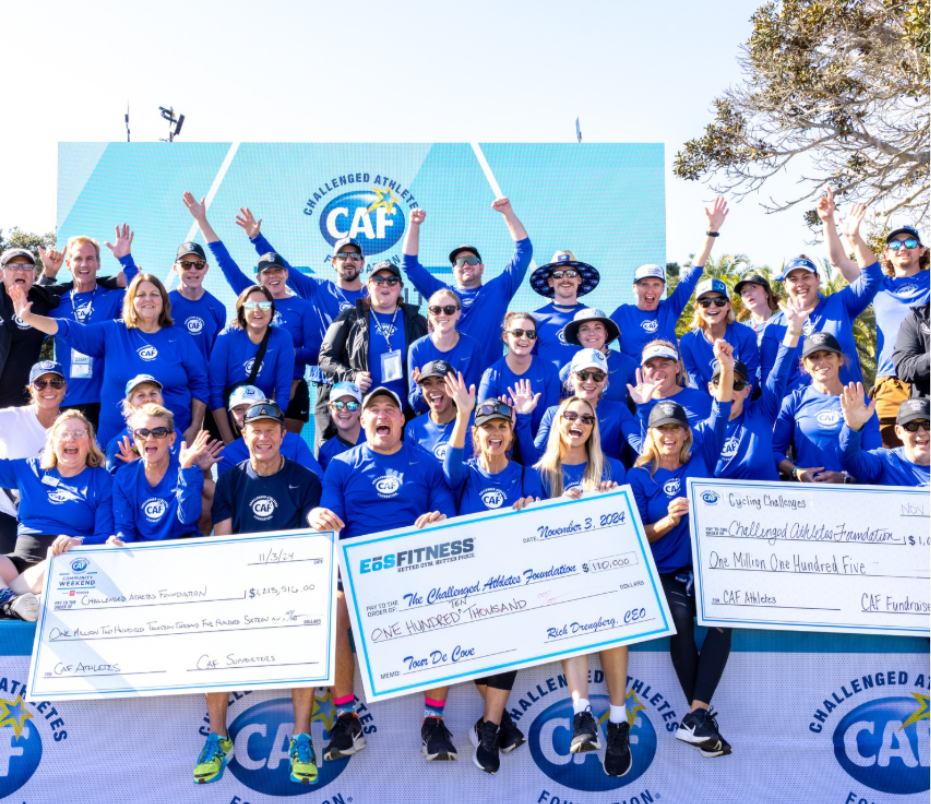 Challenged Athletes Foundation supporters holding oversized cheques at a fundraising event, with the CAF logo on the backdrop behind them