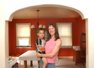 A mother holding her young son in the dining room of the home she bought after leaving public housing.
