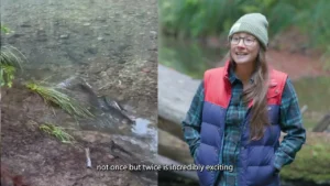 Split frame from the film. On the left a salmon lies in a shallow gravel stream. On the right a woman in a knit cap, glasses and a down vest stands beside a fallen log, with the on-screen caption not once but twice is incredibly exciting.