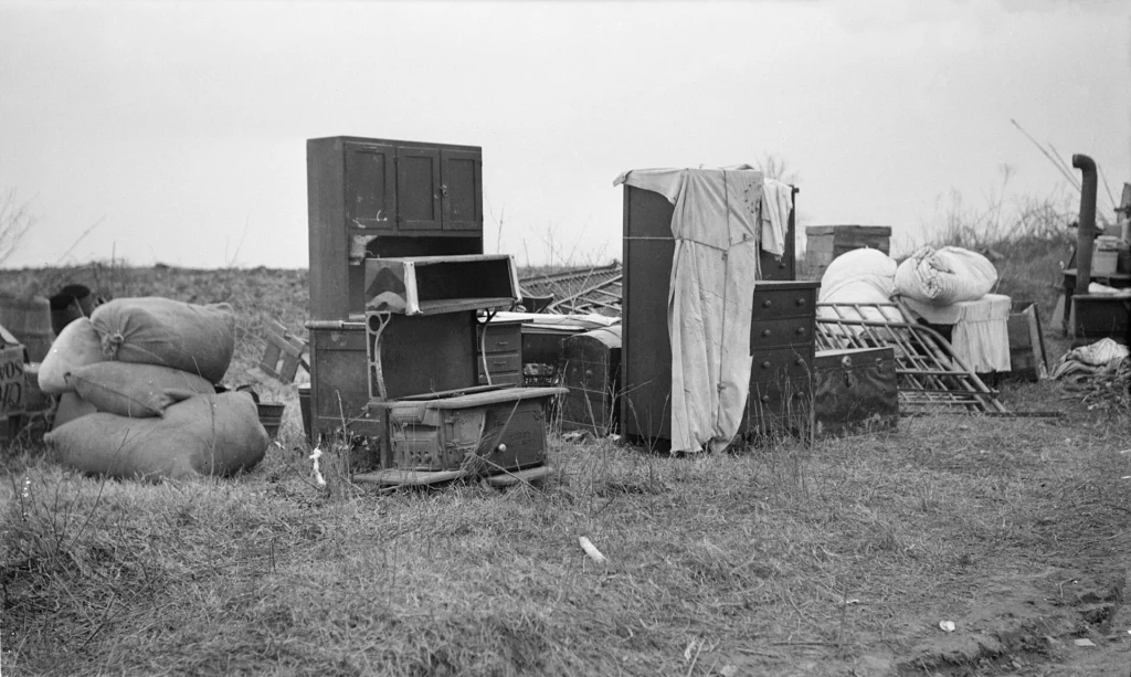 Illustration only, not Treger Strasberg's friend or any family named in this article. Furniture of evicted sharecroppers left in a field near Parkin, Arkansas, in January 1936, including a kitchen cabinet, a wood stove, a dresser, a bed frame and bundled bedding.