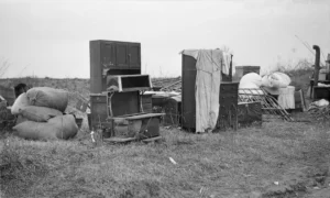 Illustration only, not Treger Strasberg's friend or any family named in this article. Furniture of evicted sharecroppers left in a field near Parkin, Arkansas, in January 1936, including a kitchen cabinet, a wood stove, a dresser, a bed frame and bundled bedding.