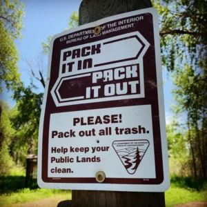 Illustration only, not a Leave No Trace photo. A Bureau of Land Management sign asking visitors to pack it in and pack it out.
